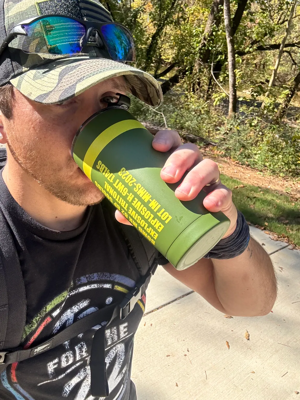 Cody Hitson drinking from his green INERTmugs tumbler while rucking on the greenway