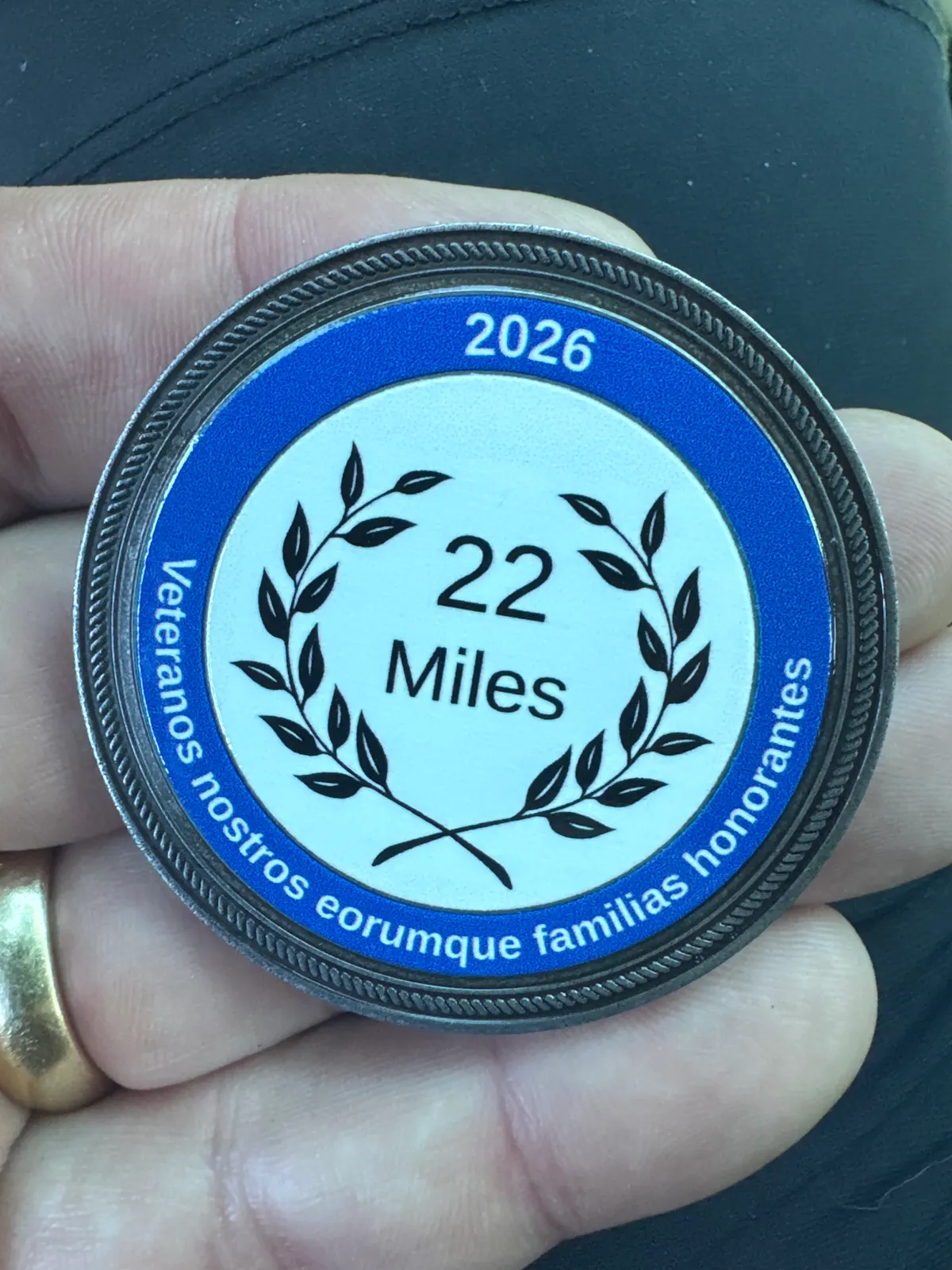 A RuckUp22 2026 challenge coin reading "22 Miles" with a laurel wreath, held in a hand